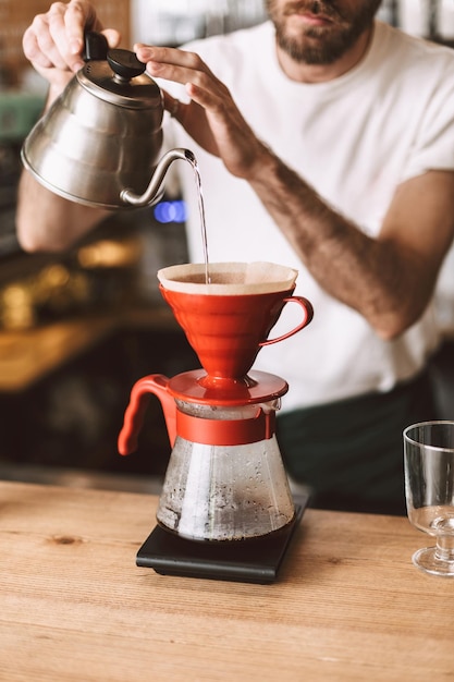 Close up photo of barista standing at counter and preparing pour over coffee in cafe