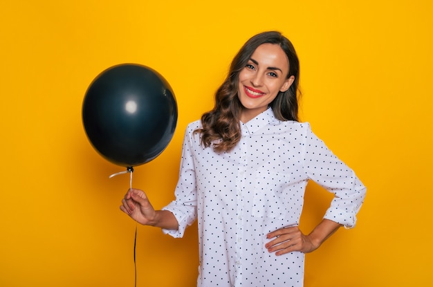 Close up photo of beautiful excited happy woman with a black helium balloon in hand like a symbol of black Friday and shopping day