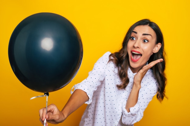 Close up photo of beautiful excited happy woman with a black helium balloon in hand like a symbol of black Friday and shopping day