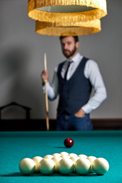 Close-up photo of billiards balls on table, focus on white balls, handsome guy