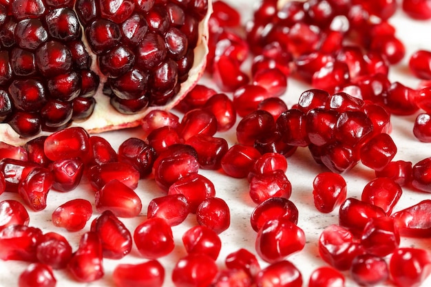 Close up photo - bright red gem like pomegranate seeds with one halved fruit in background.