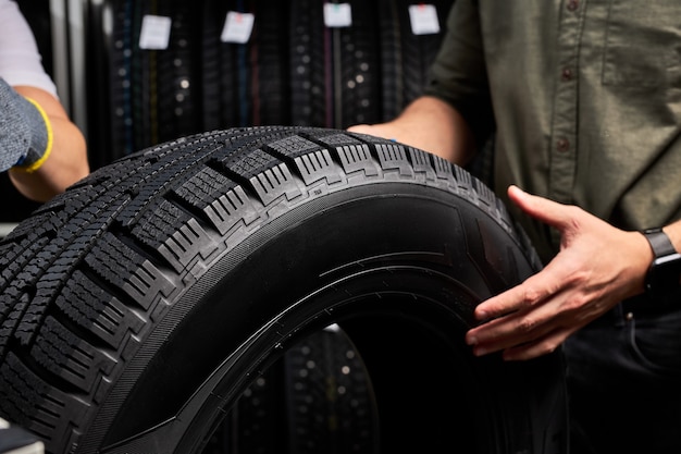 Close-up photo of car tire, focus on black tire, customer examining the surface and its characteristics before making purchase