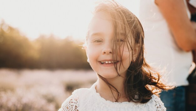 Close up photo of a caucasian girl smiling at front with a lavender field on background