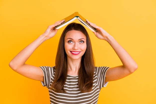 Close up photo of cheerful college student girl put her textbook above head enjoy after study free time break wear good looking clothes red pomade isolated yellow color wall