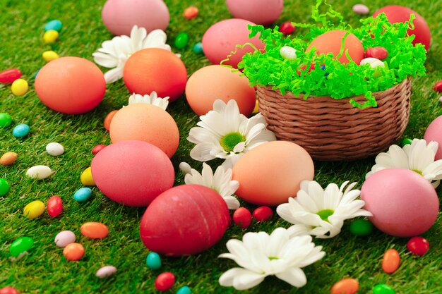 Close up photo of colored Easter eggs and candies on grass