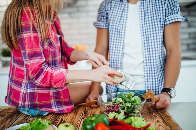 Chiuda sulla foto delle coppie che fanno la prima colazione di verdure, mani della donna che tengono la grattugia