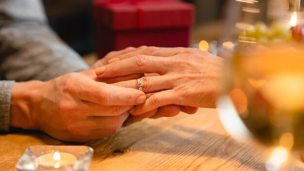 Close up photo of couples hands with engagement ring during\
romantic date