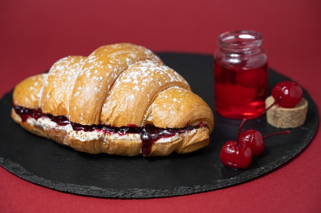 Close up photo of croissant with cherries and ingredients