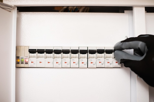 Photo close up photo of electrician hands in gloves is checking with an electrical panel with fuses