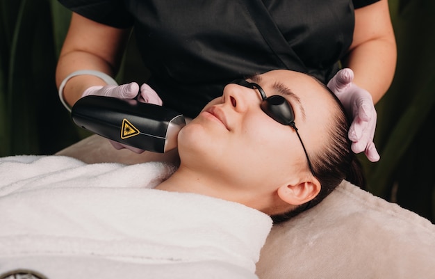 Close up photo of a facial epilation with laser using a modern device in a wellness clinic