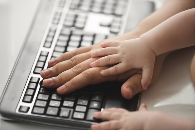 Close up photo of father and child hands using keyboard