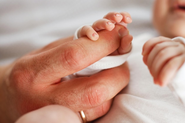 Close up photo of father holding newborn baby hand