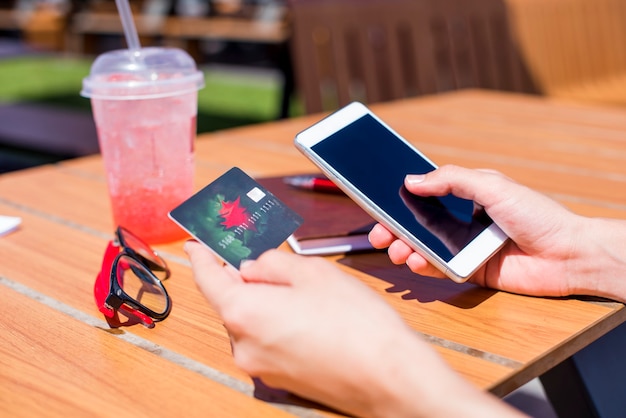 オンラインショッピングのためにスマートフォンとクレジットカードを使用して女性の手の写真を閉じる