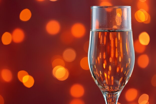 Close up photo of full Champagne glass against blurred lights