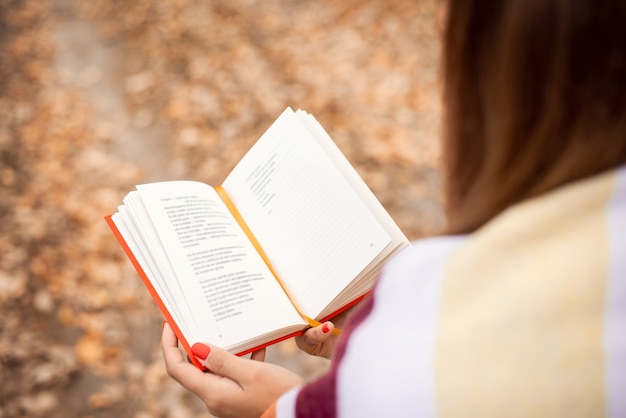 Close-up photo of a girl reading a book in an autumn park