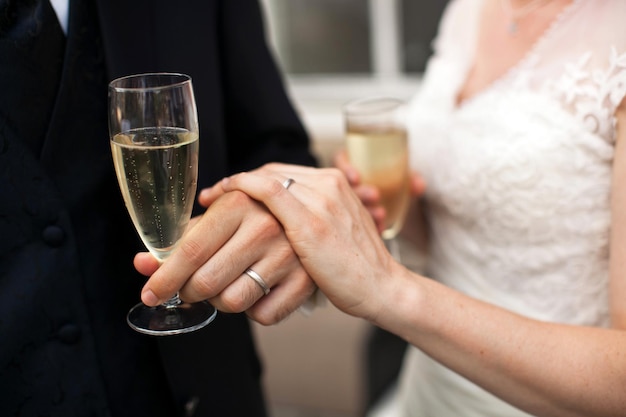 Close up photo of a groom and bride hands with a glasses of sparkling wine