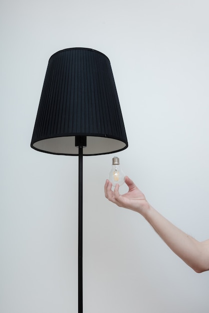 Foto ravvicinata di una mano cambia una lampadina in un'elegante lampada da soppalco