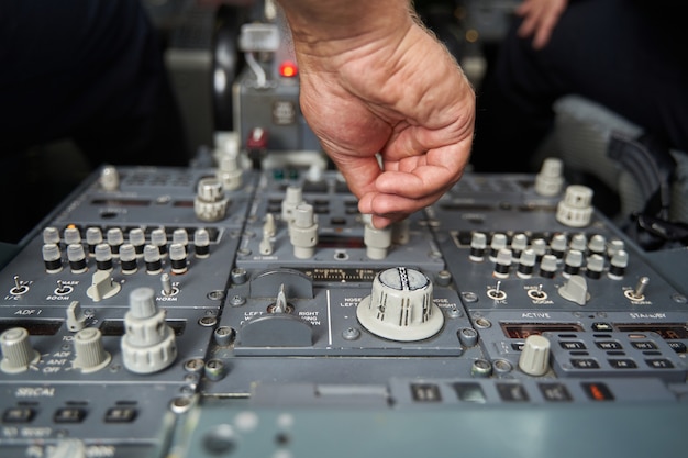 Close up photo hand of the professional pilot on a control panel in the cockpit