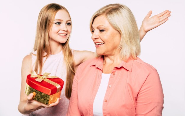 Close up photo of happy grandmother and granddaughter in good and fun mood isolated together on white background. I love my grandma. Family holidays and celebrations