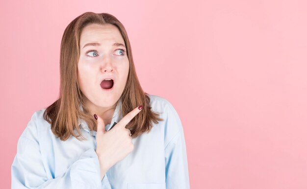 Primo piano foto della signora colpita che mostra un incredibile grido di raccomandazioni in camicia blu sul rosa