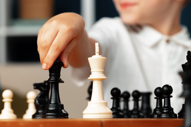 Close up photo of a little boy playing chess