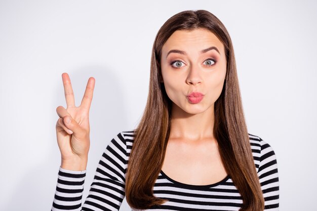 Close up photo of lovely person making v-sign wearing striped pullover isolated over white wall