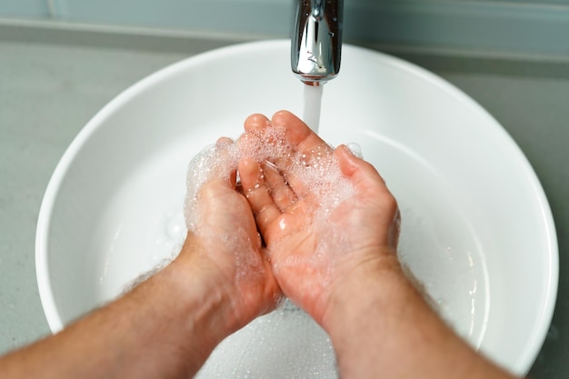 Foto foto da vicino di mani maschili che si lavano con il sapone sopra il lavandino