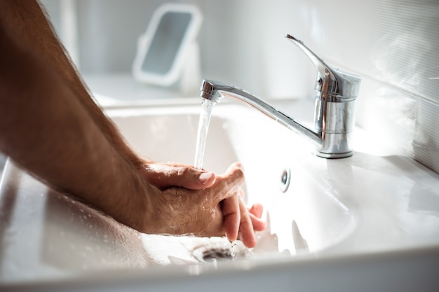 Close up photo of males hands with soap in the wash basin. Safety health procedure, pandemic, antibacterial.