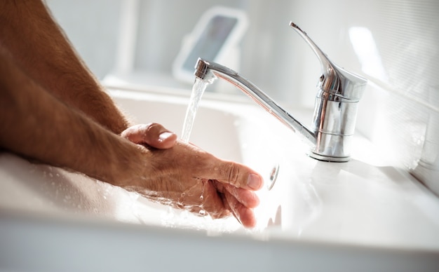 洗面台に石鹸で男性の手の写真をクローズアップ。安全健康処置、パンデミック、抗菌。