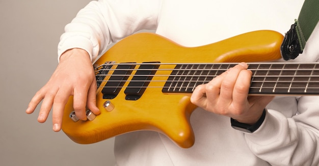 Close up photo of man adjusting volume at bass guitar