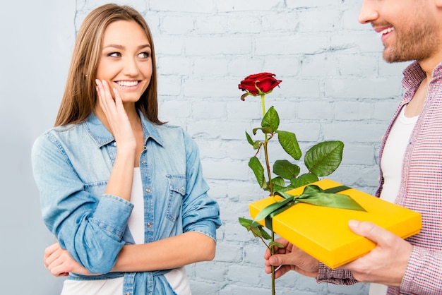 Close up photo of man giving gift and rose to his girl