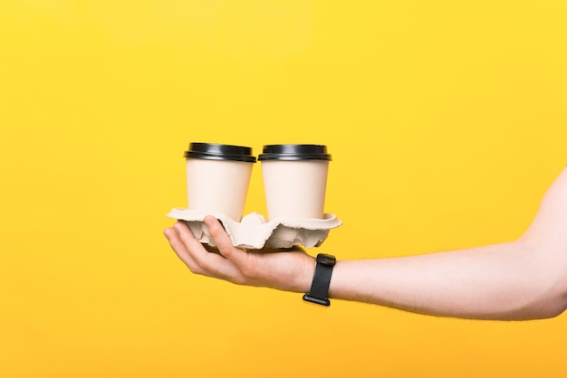 Close up photo of man hand holding two paper cups of coffee to go