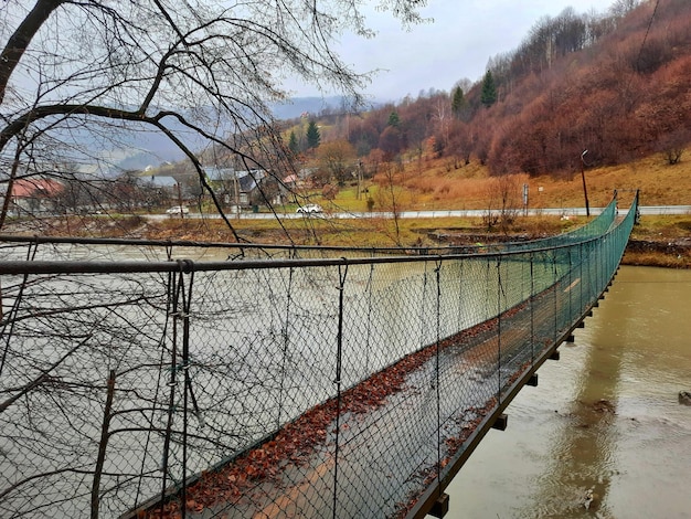 Close-up photo of an old bridge over a mountain river, on the back of coniferous green trees and mou