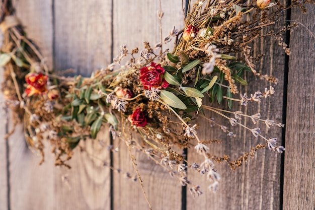 Photo close up photo part of twisted crafting arvensis creative dry herbal wreath from twigs of wild flowers cereal and grass traditional festive ethnic decoration on entrance door low angle view