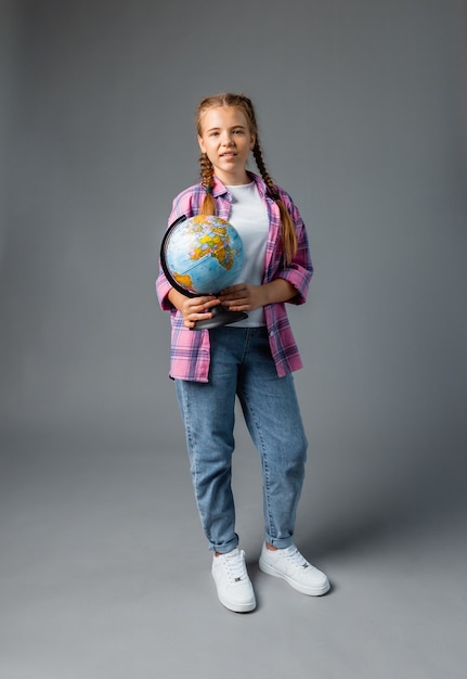 Close up photo portrait of funny cute laughing smart surprised girl holding globe in hands