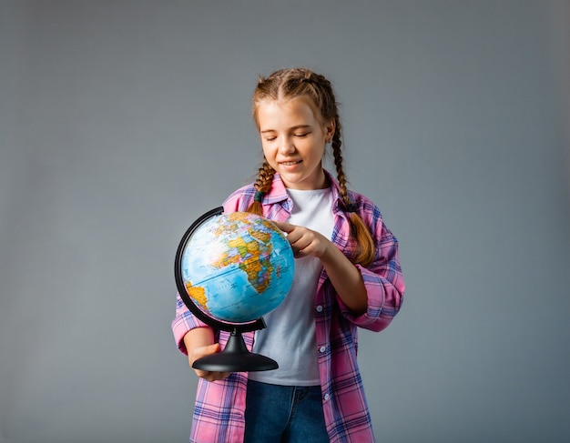 Close up photo portrait of funny cute laughing smart surprised girl holding globe in hands