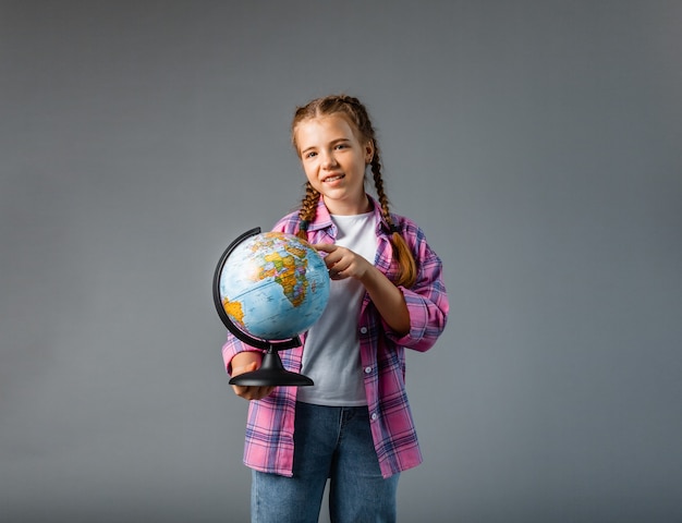 Close up photo portrait of funny cute laughing smart surprised girl holding globe in hands