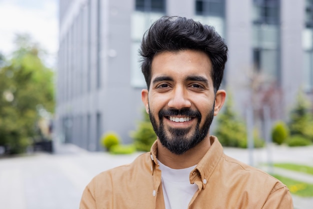 Close up photo portrait of young hindu student man smiling and looking at camera businessman outside