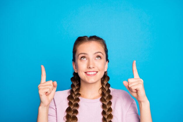 Photo close up photo of positive cheerful girl promoter point index finger copy space look up give feedback about promo indicate news information wear pink sweater isolated over blue color background