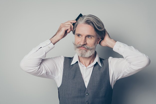 Close up photo positive old man combing his hair