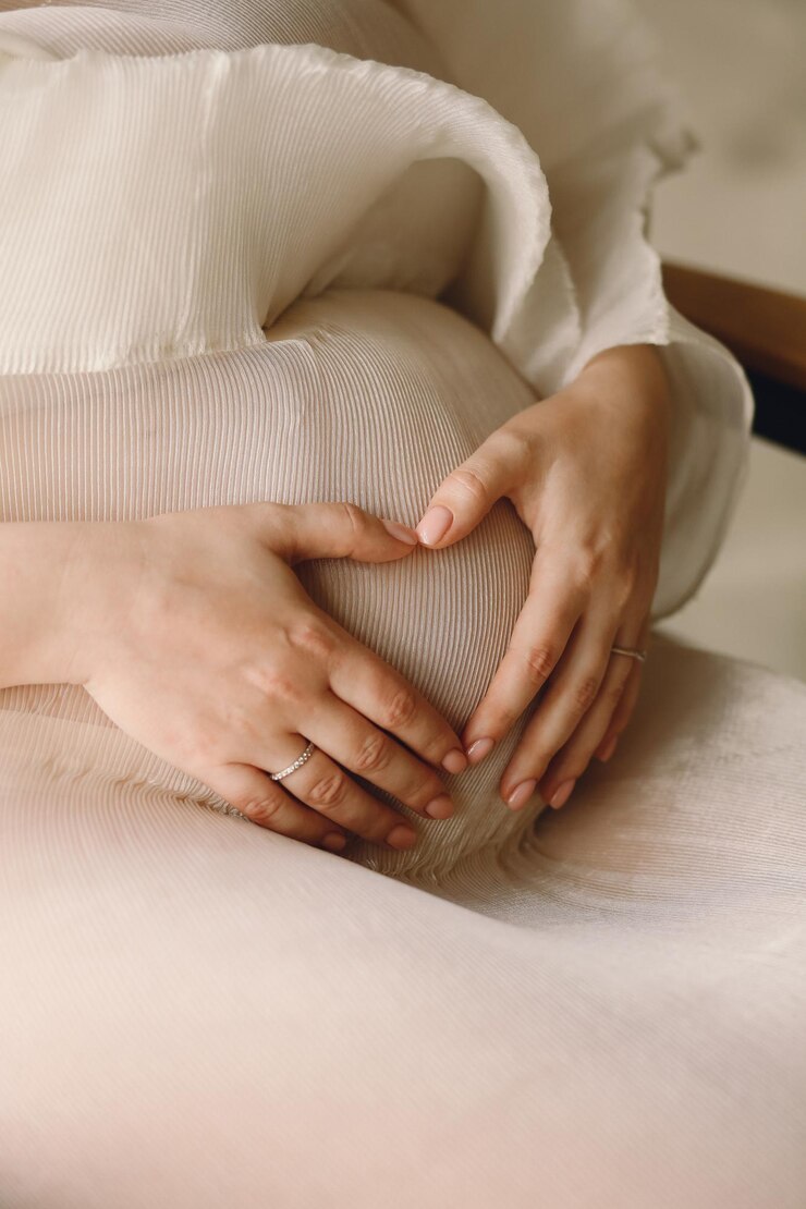 Photo 手を腹に置いて心の形をした妊娠中の女性のクローズアップ写真