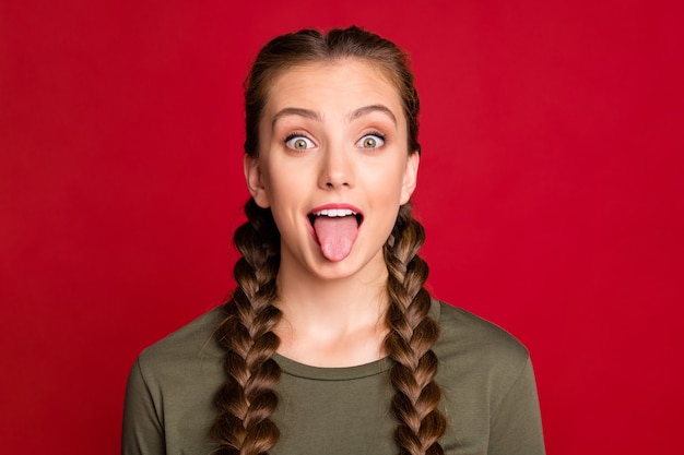 Close up photo of pretty teen model lady playing with classmate sticking tongue out mouth wear casual pullover isolated red color background