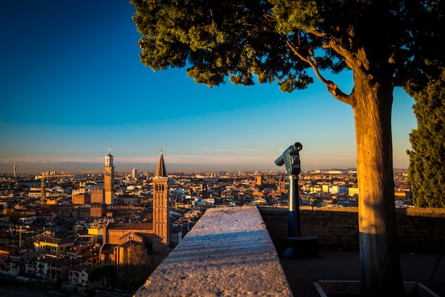 A close up photo of a public monocular on the top of a mountain with spectacular aerial views of the old city of Verona in Italy Morning gold sunrise