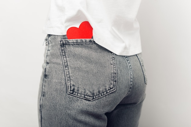 Крупным планом фото сердца из красной бумаги в заднем кармане брюк