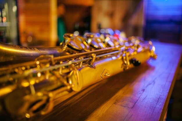 Close up photo of a shiny golden saxophone. Vintage Saxophone. Golden soprano Saxophone. Wind musical instrument. Beautiful golden saxophone on wooden background