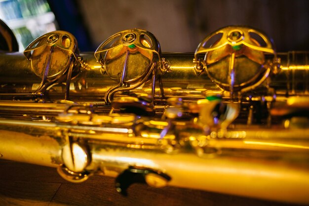Крупным планом фото блестящего золотого саксофона. Винтажный саксофон. Золотое сопрано Саксофон. Духовой музыкальный инструмент. Красивый золотой саксофон на деревянных фоне