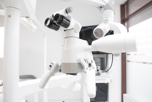 Крупным планом фото какого-то белого стоматологического оборудования с биноклем, снятого в чистой клинике