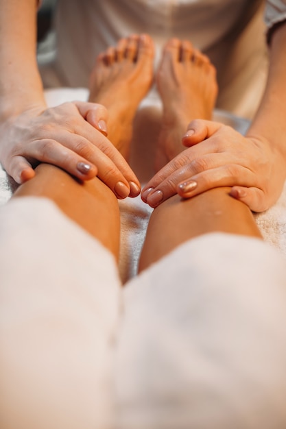 Close up photo of spa massage session made by a careful worker at the salon on the client's legs