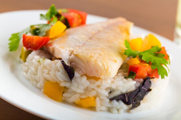 Close-up photo of tasty fish with vegetables and rice in white plate