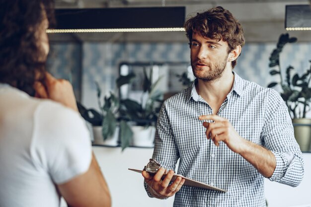 Close up photo of two male colleagues discussing project in office